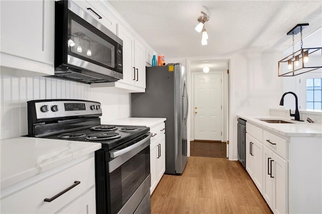 4017 Cottage Hill Rd Unit 17, Mobile, AL 36609 - kitchen with appliances with stainless steel finishes, light wood finished floors, white cabinetry, hanging light fixtures, and light stone countertops