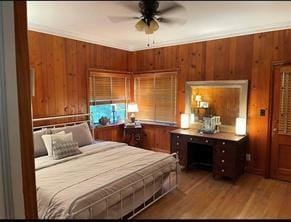 bedroom with hardwood / wood-style flooring, ceiling fan, and wooden walls