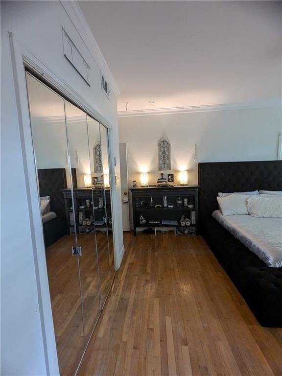 bedroom featuring hardwood / wood-style floors, ornamental molding, and a closet