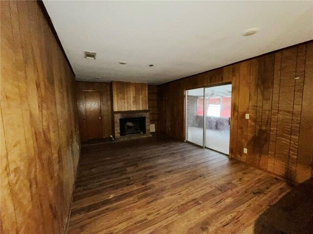 unfurnished living room with dark wood-type flooring and wooden walls