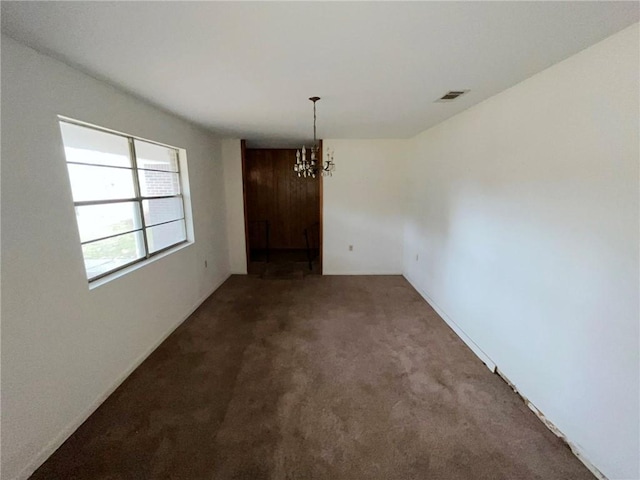 carpeted spare room with a chandelier