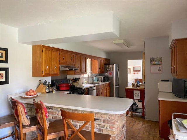 kitchen with kitchen peninsula, sink, stainless steel appliances, and a breakfast bar