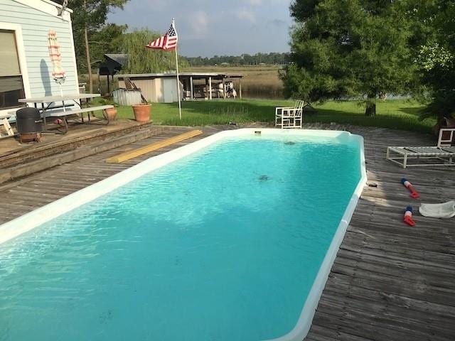 view of pool featuring a deck and a storage unit