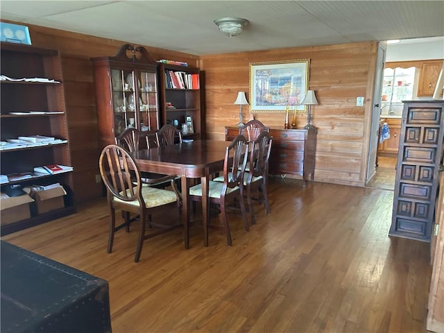 dining space with wood walls and wood-type flooring