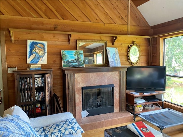 living room featuring hardwood / wood-style flooring, lofted ceiling, plenty of natural light, and a tiled fireplace