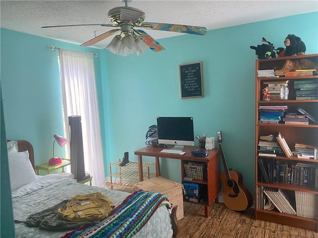 bedroom featuring ceiling fan, wood-type flooring, and a textured ceiling