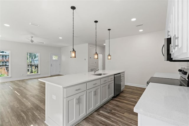 kitchen with a center island with sink, sink, dark wood-type flooring, appliances with stainless steel finishes, and pendant lighting