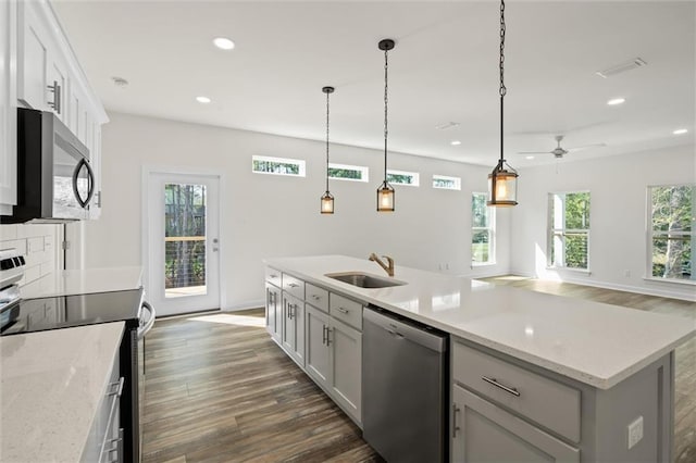 kitchen featuring appliances with stainless steel finishes, a center island with sink, pendant lighting, sink, and white cabinetry