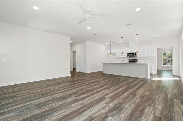 unfurnished living room featuring ceiling fan and dark hardwood / wood-style floors