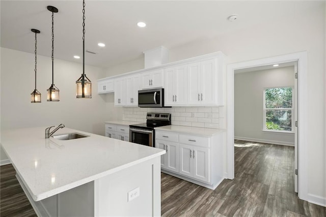 kitchen featuring a kitchen island with sink, stainless steel appliances, sink, white cabinets, and pendant lighting