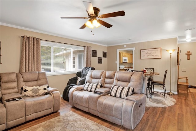 living room with ornamental molding, ceiling fan, and light hardwood / wood-style floors