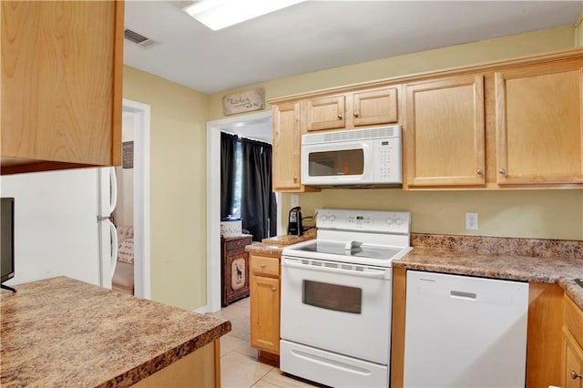 kitchen featuring light tile patterned floors, light brown cabinetry, and white appliances