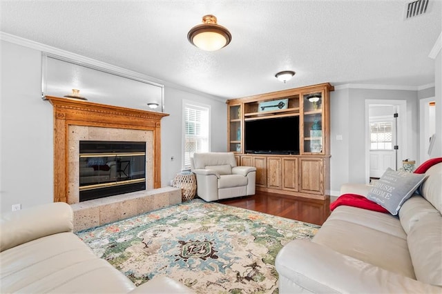 living room with a textured ceiling, a premium fireplace, dark wood-type flooring, and crown molding