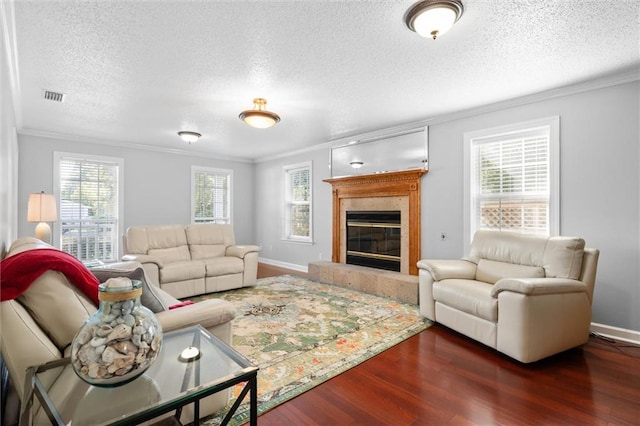 living room featuring a tiled fireplace, a textured ceiling, plenty of natural light, and dark hardwood / wood-style flooring