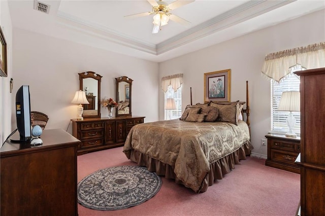 bedroom featuring ceiling fan, ornamental molding, a tray ceiling, and carpet floors