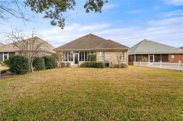 rear view of property with a sunroom and a lawn