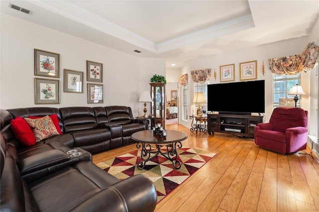 living room featuring a raised ceiling, wood-type flooring, and crown molding