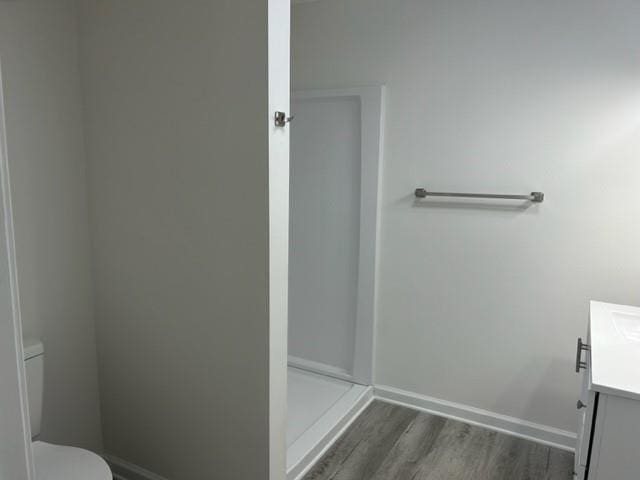 bathroom featuring vanity, toilet, wood-type flooring, and a shower