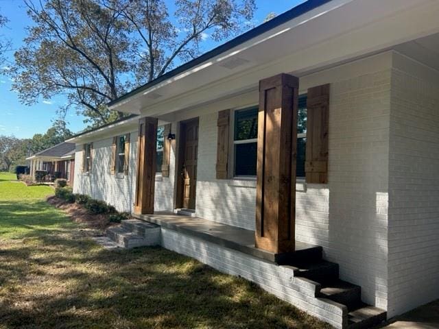 property entrance featuring a yard and a porch