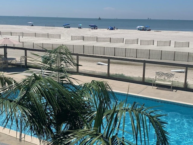 view of swimming pool with a water view and a view of the beach