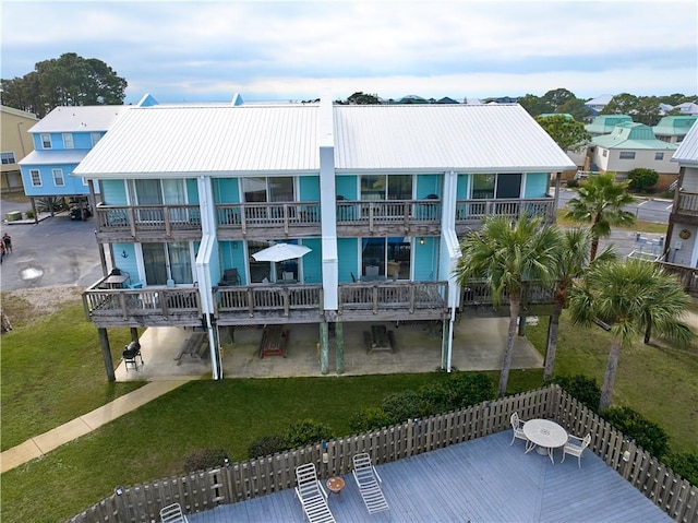 rear view of house with a carport, a balcony, and a yard