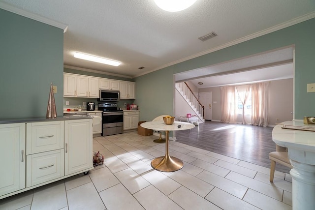 kitchen with white cabinets, crown molding, light tile patterned floors, a textured ceiling, and appliances with stainless steel finishes