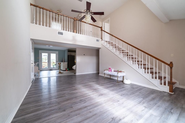 unfurnished living room with french doors, a towering ceiling, ceiling fan, and dark wood-type flooring