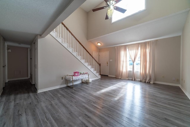 unfurnished living room with a textured ceiling, ceiling fan, and dark wood-type flooring