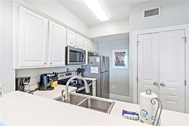 kitchen with white cabinetry, sink, kitchen peninsula, a textured ceiling, and appliances with stainless steel finishes