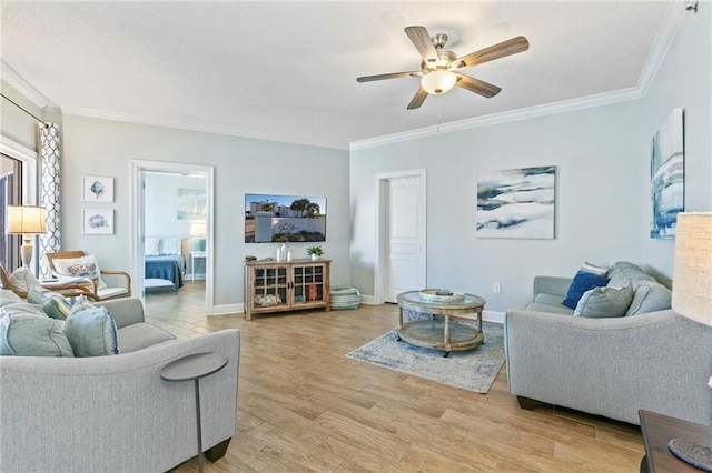 living room with ceiling fan, ornamental molding, and light hardwood / wood-style flooring