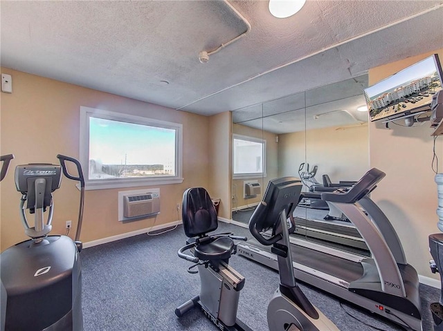 gym featuring a wall unit AC, carpet, and a textured ceiling