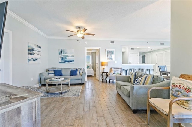 living room featuring ceiling fan, ornamental molding, and light hardwood / wood-style flooring