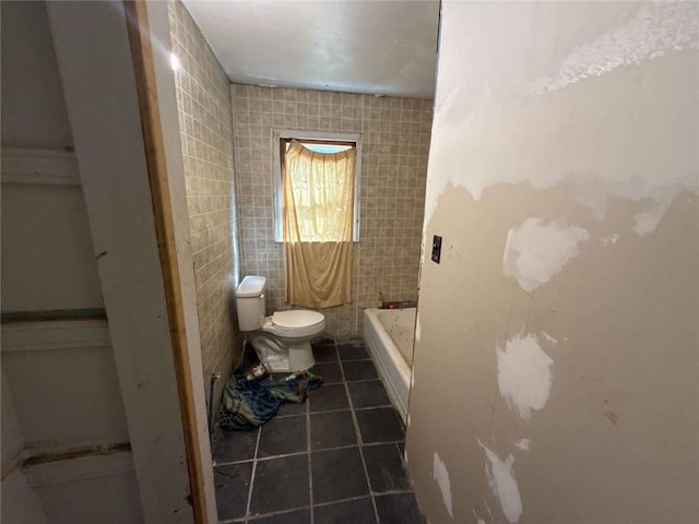 full bathroom featuring toilet, a bathtub, tile walls, and tile patterned floors