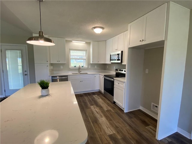 kitchen with appliances with stainless steel finishes, pendant lighting, light countertops, and white cabinetry