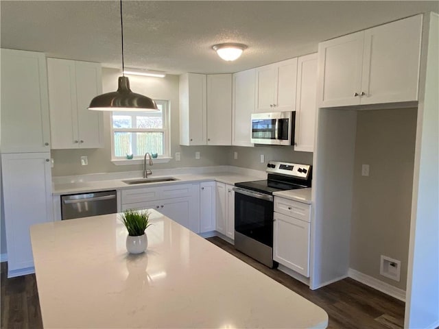 kitchen with hanging light fixtures, stainless steel appliances, a sink, and light countertops