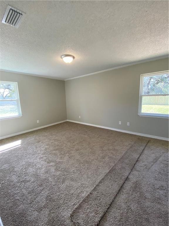 carpeted empty room featuring baseboards, visible vents, and a textured ceiling