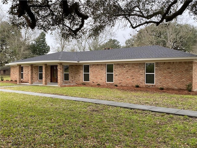 ranch-style house featuring roof with shingles, a front yard, and brick siding