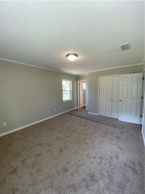 unfurnished bedroom with visible vents, baseboards, a closet, dark carpet, and crown molding