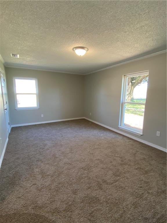 spare room featuring baseboards, visible vents, ornamental molding, dark colored carpet, and a textured ceiling