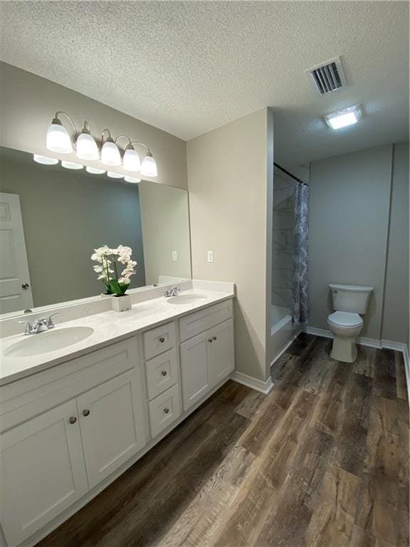 full bathroom featuring wood finished floors, visible vents, a sink, and double vanity