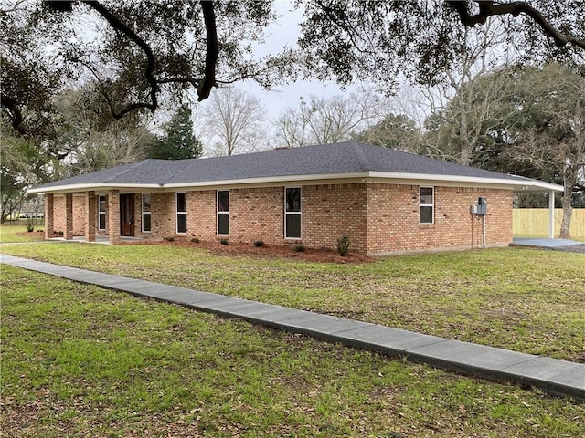 view of front of home with a front yard, brick siding, and roof with shingles