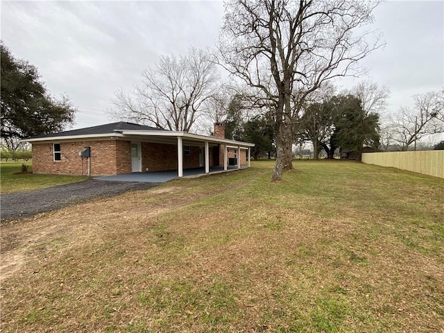 view of yard with driveway, a carport, and fence