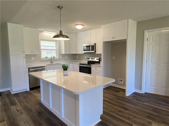 kitchen with white cabinets, appliances with stainless steel finishes, a center island, light countertops, and pendant lighting