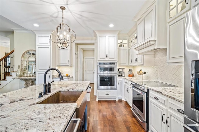 kitchen featuring stainless steel appliances, white cabinetry, light stone countertops, and pendant lighting