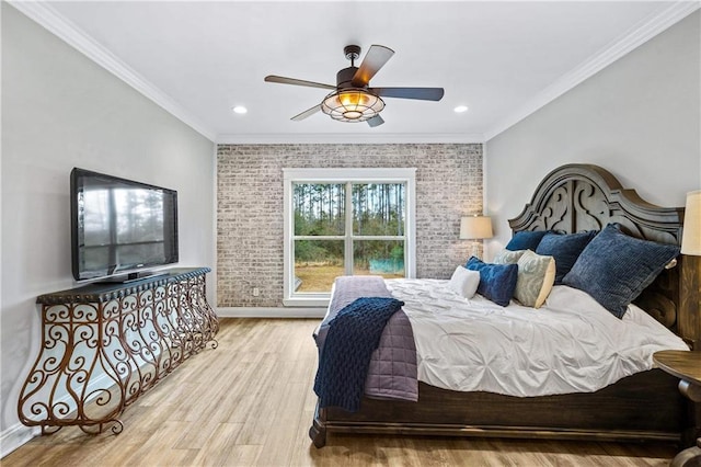 bedroom featuring crown molding, light hardwood / wood-style floors, ceiling fan, and brick wall