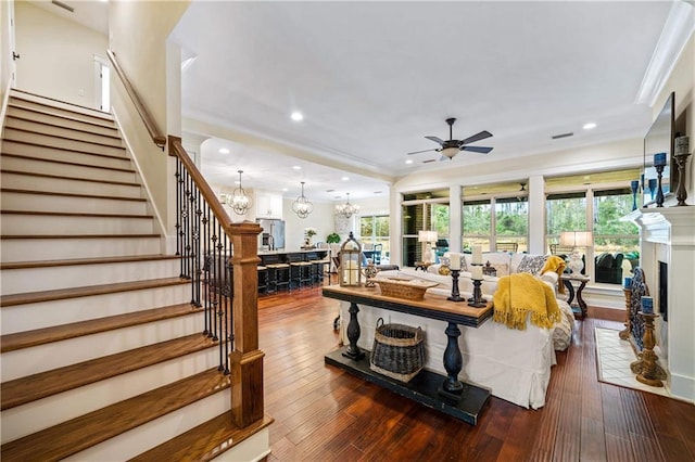 living room with a healthy amount of sunlight, dark hardwood / wood-style floors, and ceiling fan with notable chandelier