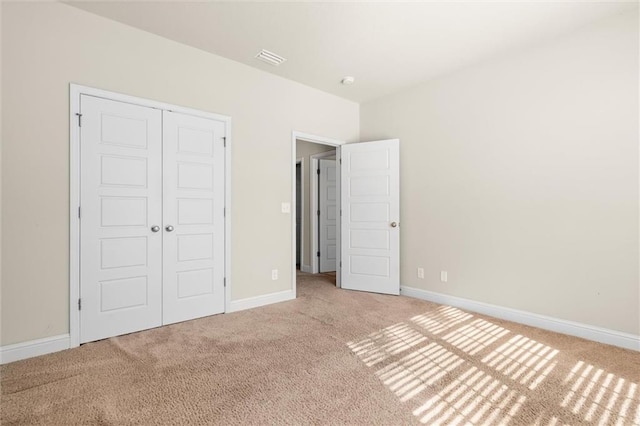 unfurnished bedroom featuring light colored carpet and a closet