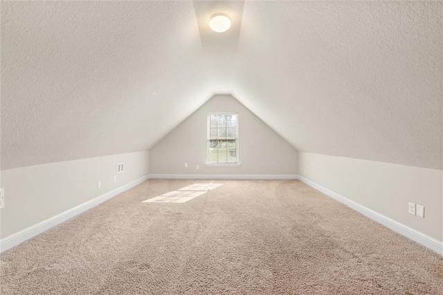 additional living space with a textured ceiling, light colored carpet, and lofted ceiling