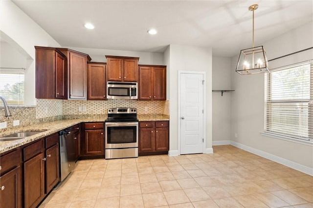 kitchen featuring pendant lighting, an inviting chandelier, sink, light stone countertops, and appliances with stainless steel finishes