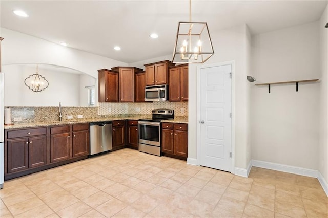 kitchen featuring light stone countertops, sink, stainless steel appliances, a chandelier, and pendant lighting